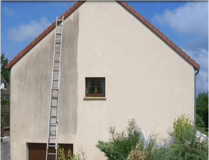 House exterior with a ladder against the wall, showing a partially cleaned surface.