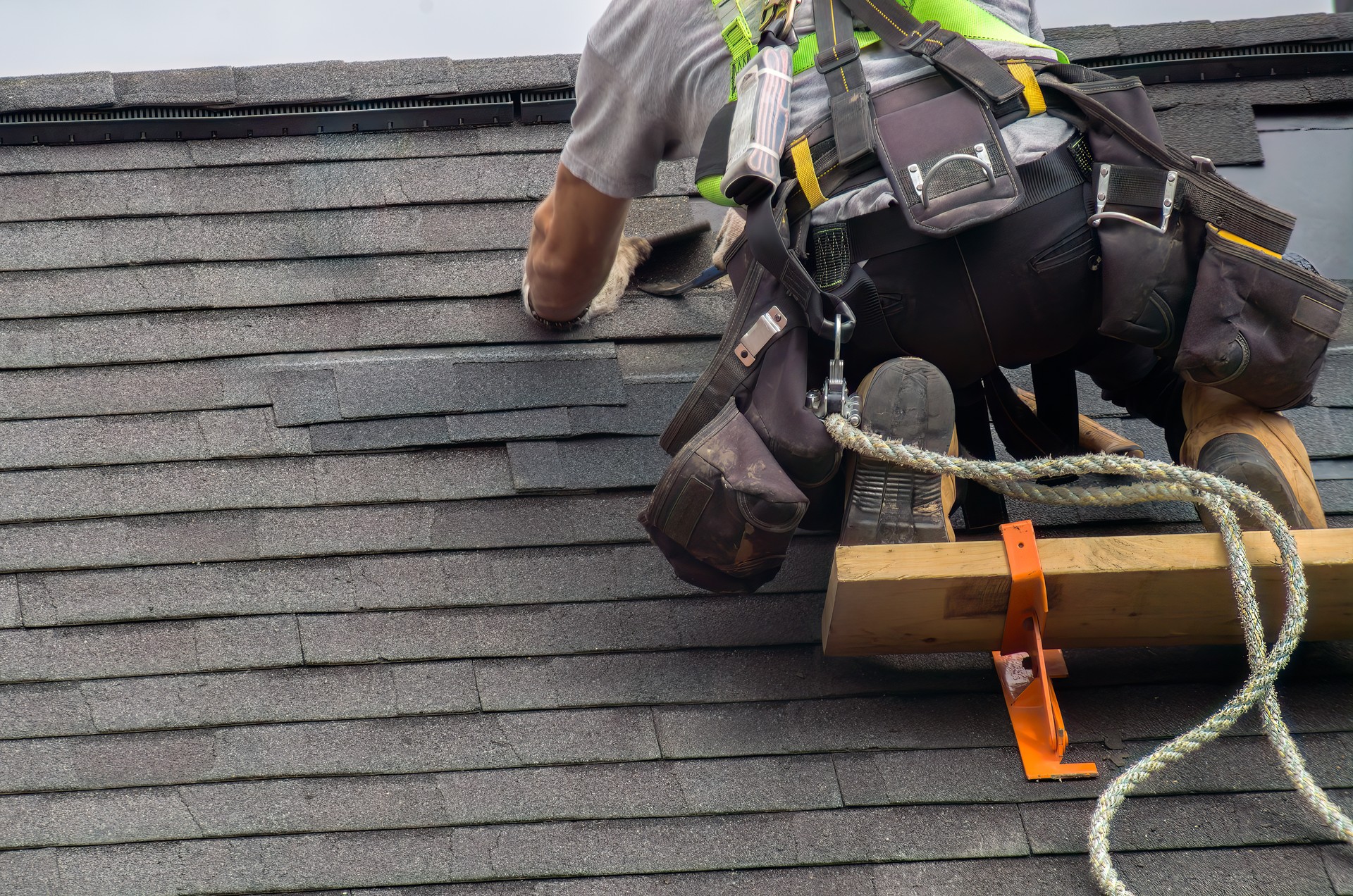 Couvreur Ouvrier de la construction assurant l’entretien du toit avec une corde de sécurité